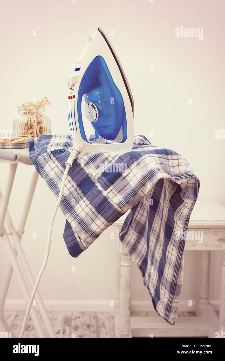 Shirt mit Eisen an Bord mit Glas Heringe frisch gepresst Stockfoto