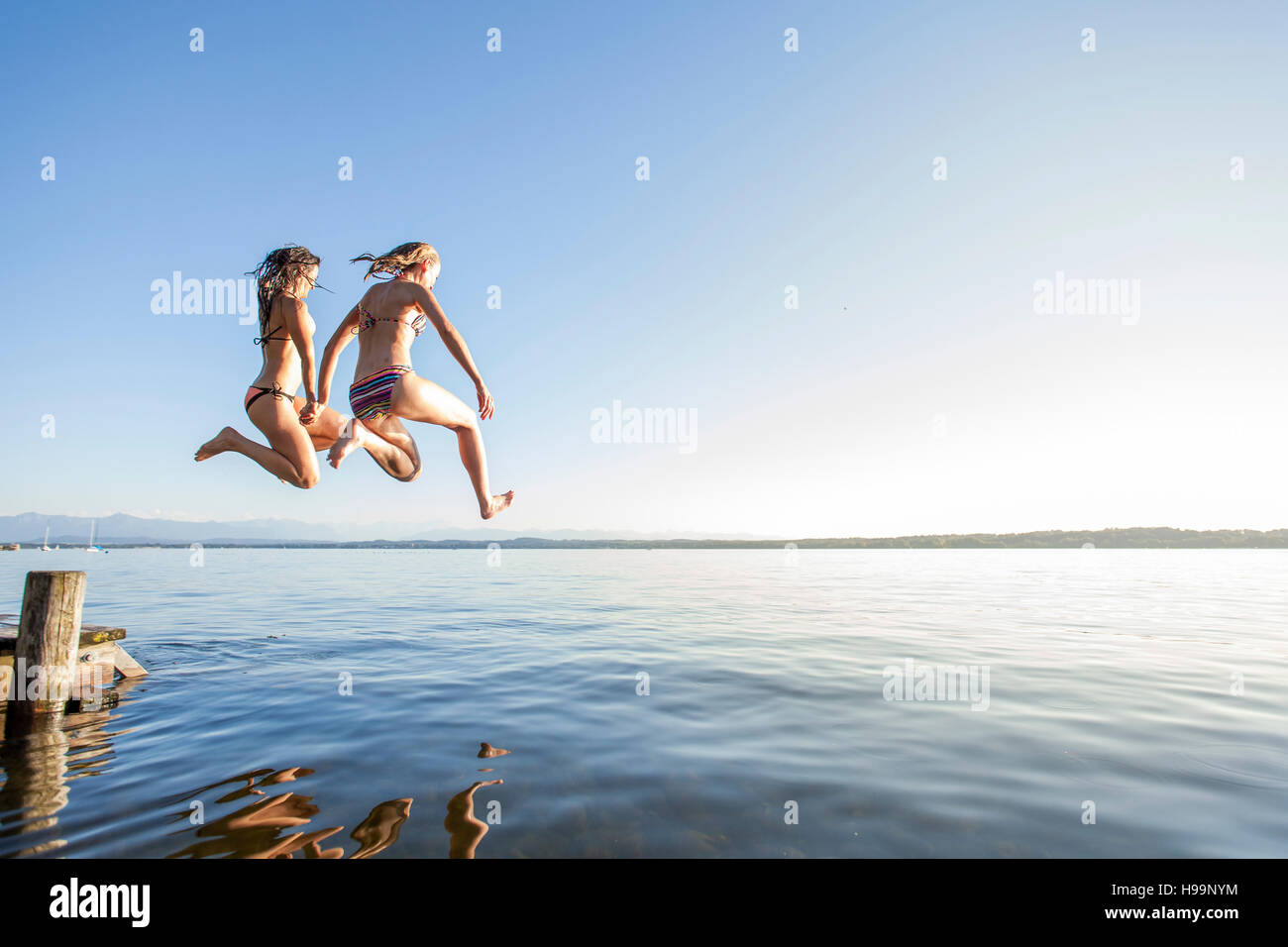 Zwei junge Frauen, die in den See springen Stockfoto