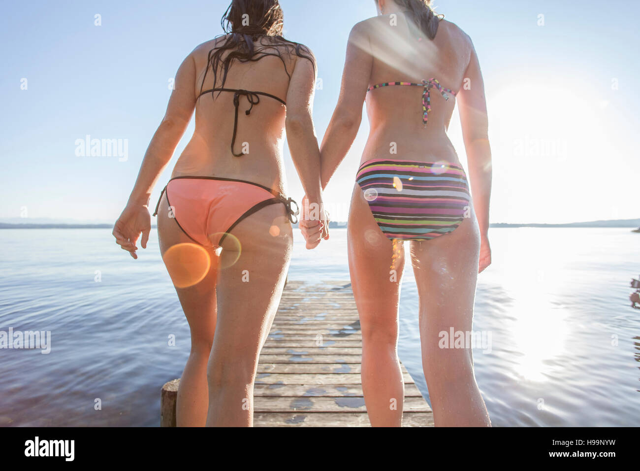 Zwei junge Frauen gehen auf Pier Hand in Hand Stockfoto