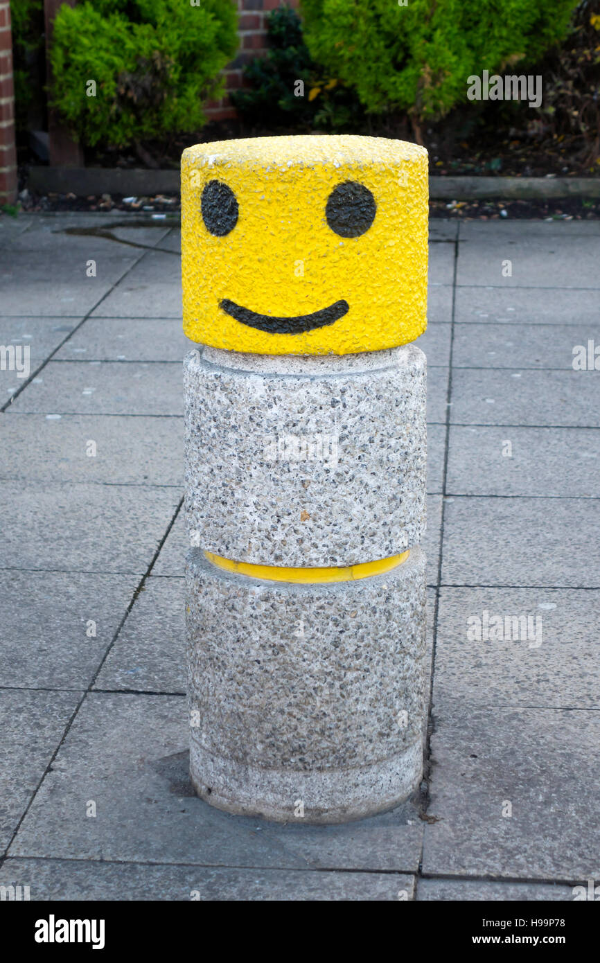 Eine Pflaster Poller mit einer gelben und schwarzen Smiley-Gesicht gemalt. Stockfoto