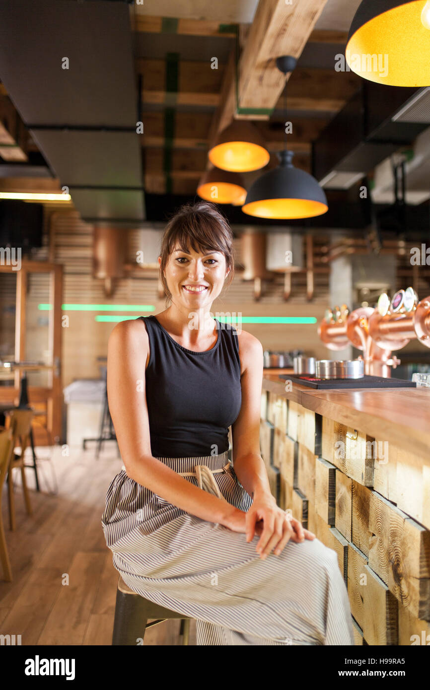 Frau mit braunen Haaren sitzt am Tresen in Coffee-shop Stockfoto