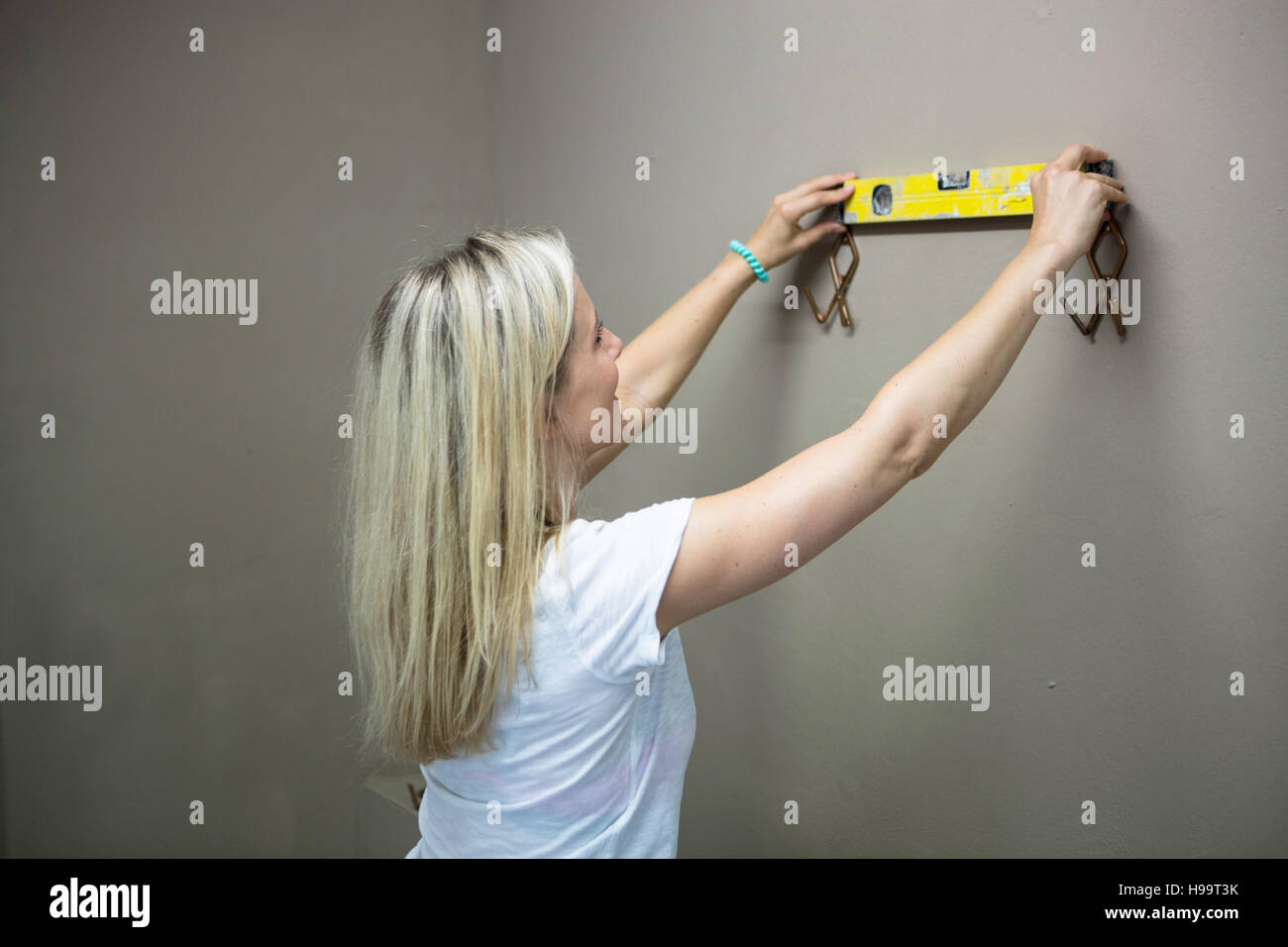 Blonde Frau mit Wasserstand messen, Kleiderhaken zu beheben Stockfoto