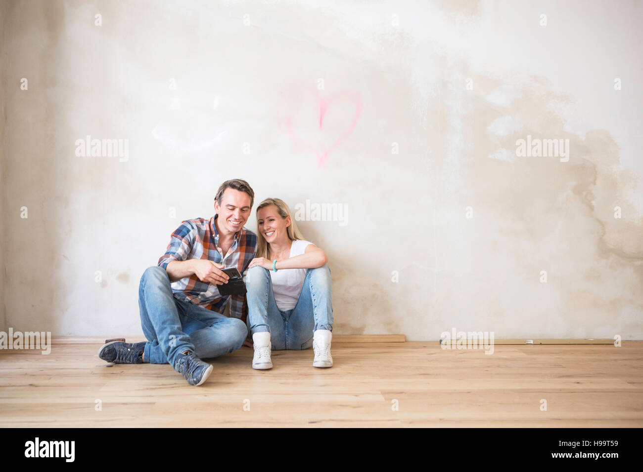 Junges Paar nimmt sich eine Auszeit auf Hartholz-Fußboden sitzen Stockfoto