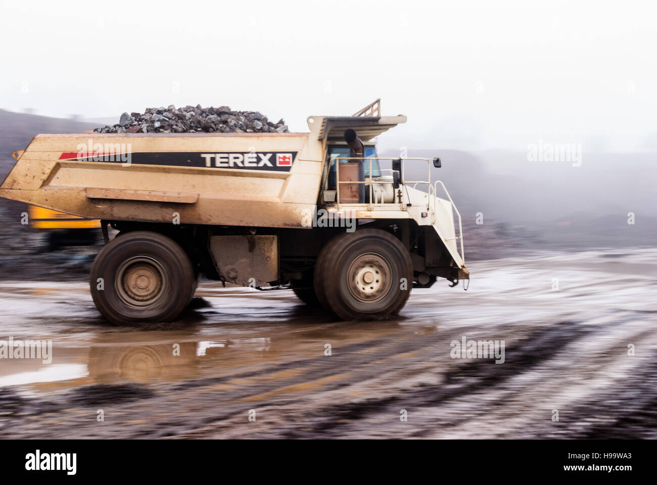 Ein Muldenkipper Terex Rock dauert eine volle Ladung aus Stein in einem Steinbruch bei starkem Regen. Stockfoto