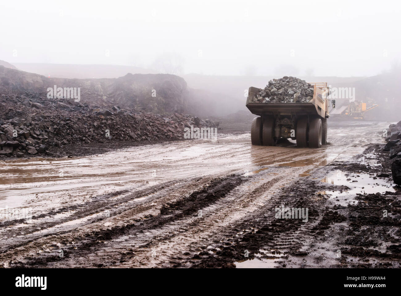 Ein Muldenkipper Terex Rock dauert eine volle Ladung aus Stein in einem Steinbruch bei starkem Regen. Stockfoto