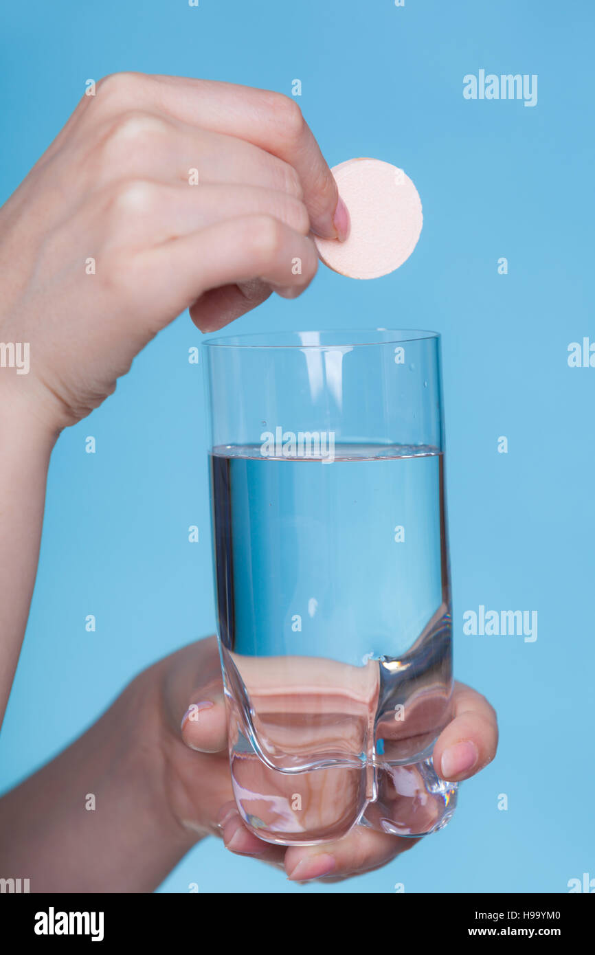 Vitamine, Gesundheit, Medikamente. Person werfen Vitamin Mineral ergänzen Brausetablette in einem Glas Wasser. Studio gedreht auf blauem Hintergrund Stockfoto