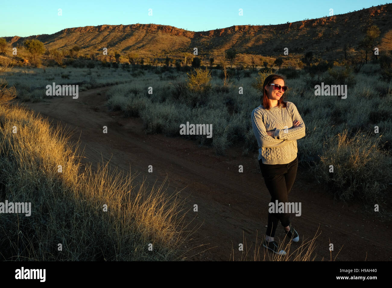 Eine Frau beobachtet den Sonnenuntergang in den MacDonnell Ranges, Alice Springs, Northern Territory, Zentral-Australien Stockfoto