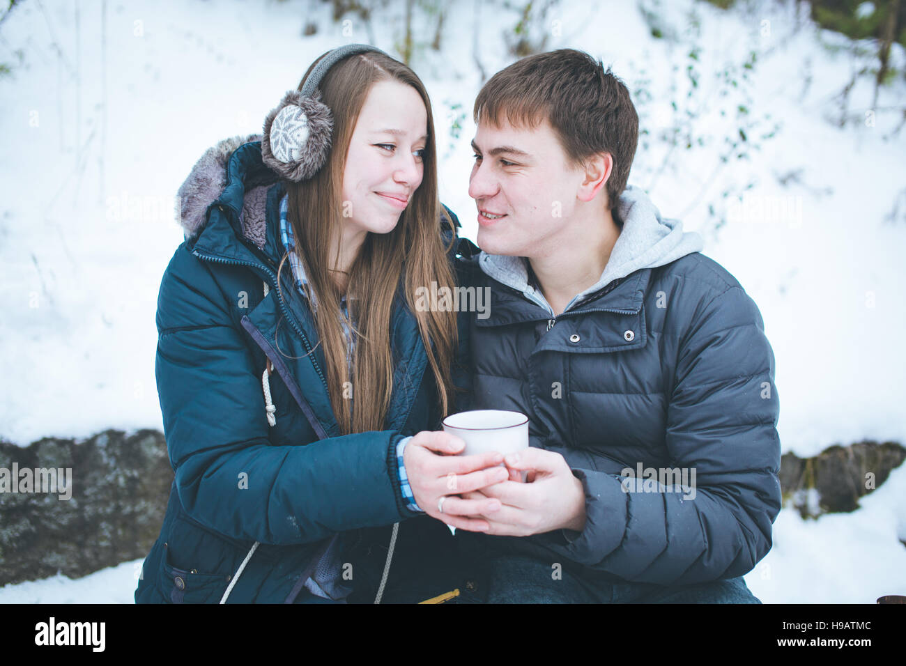 Liebende Paare, die Spaß im Freien im Winter halten große Tasse mit heißem Tee Stockfoto