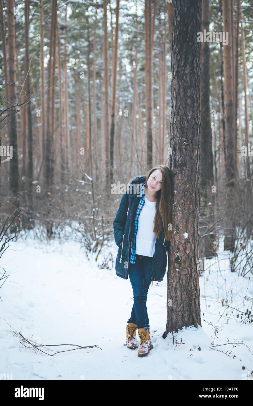 Natürliche junge Frau im Winterwald wandern zwischen Bäumen Stockfoto