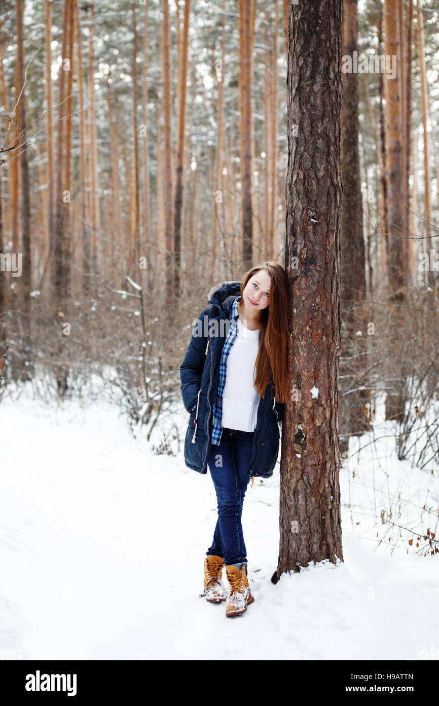 Natürliche junge Frau im warmen Freizeitkleidung im Winterwald wandern zwischen Bäumen Stockfoto