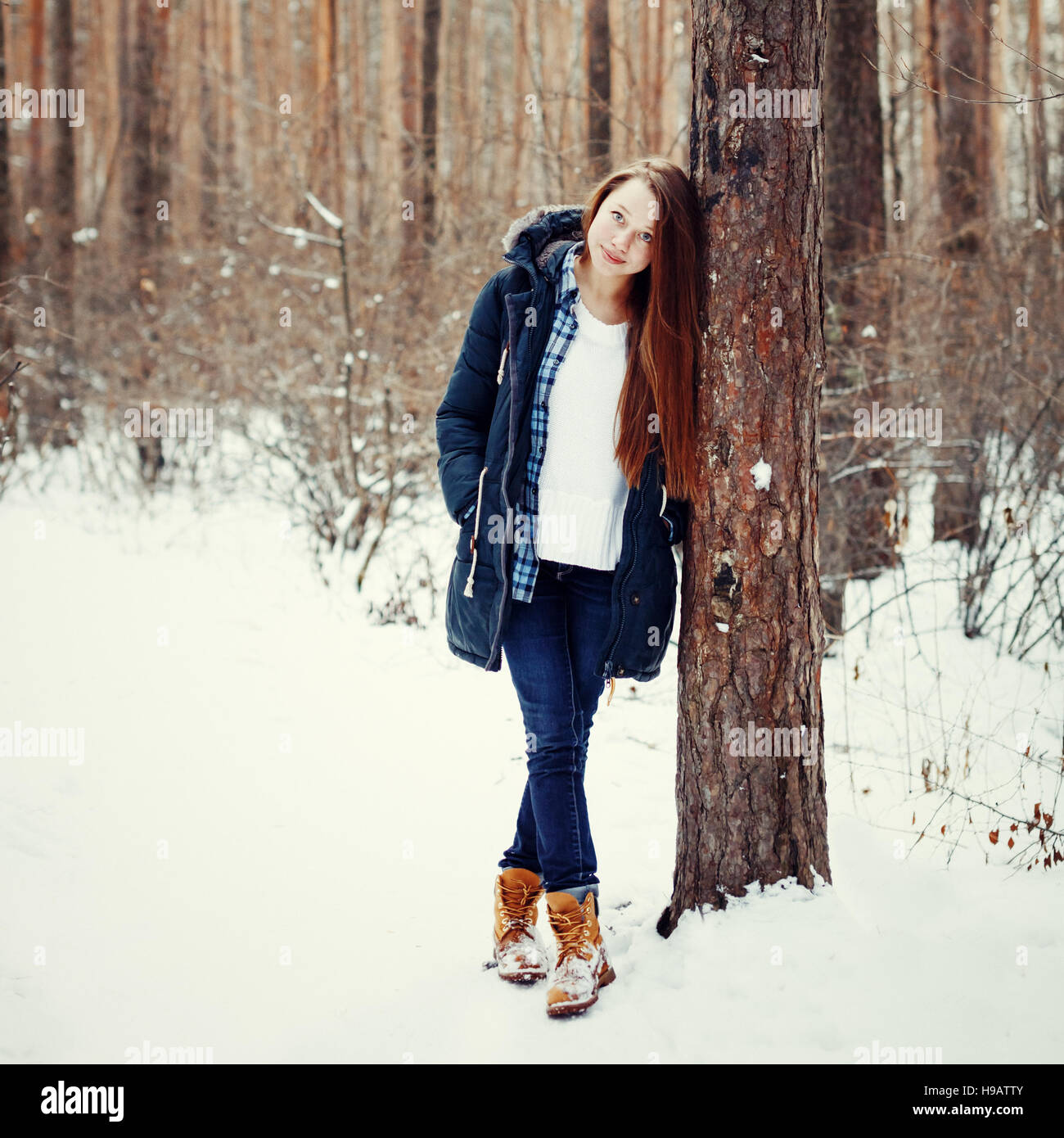 Natürliche junge Frau im Winterwald wandern zwischen Bäumen, getönt Stockfoto