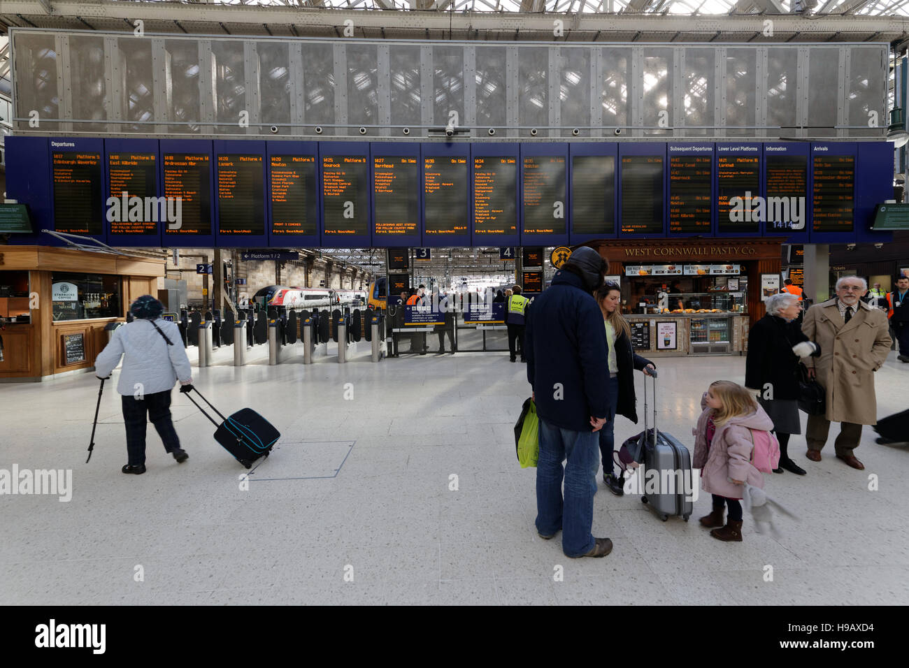 Familie in Glasgow Hauptbahnhof Bahnhof telefonieren suchen Ankünfte board Stockfoto