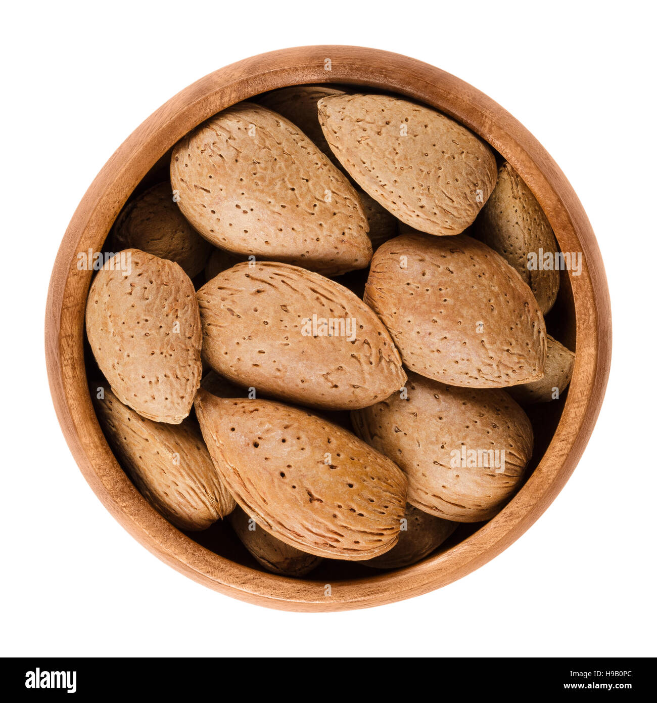 Mandeln in der Schale in einer Holzschale auf weißem Hintergrund. Die rohen essbaren Mandel Samen sind keine Muttern. Sie sind botanisch Steinfrüchte. Stockfoto