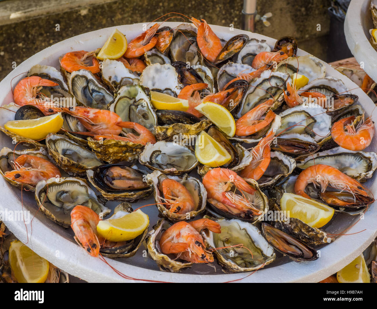 Fischplatte von Garnelen und rohe Austern, abgerundet mit Zitronenscheiben Stockfoto