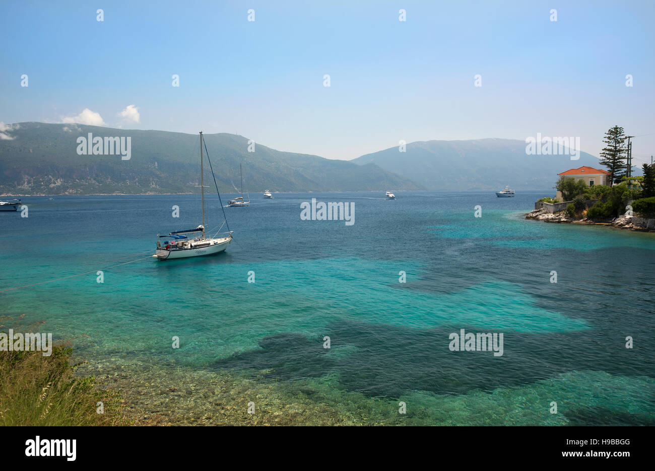 Boote in das türkisfarbene Wasser in Fiscardo, auf der Insel Kefalonia, in Griechenland, mit Blick auf die Insel Ithaka Stockfoto
