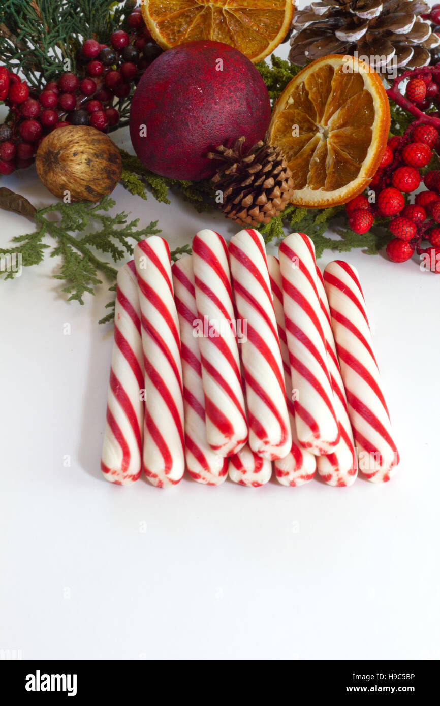 Stick Pfefferminz Zuckerstangen gestapelt auf weißem Hintergrund mit festlichen Weihnachtsschmuck im Hintergrund isoliert Stockfoto