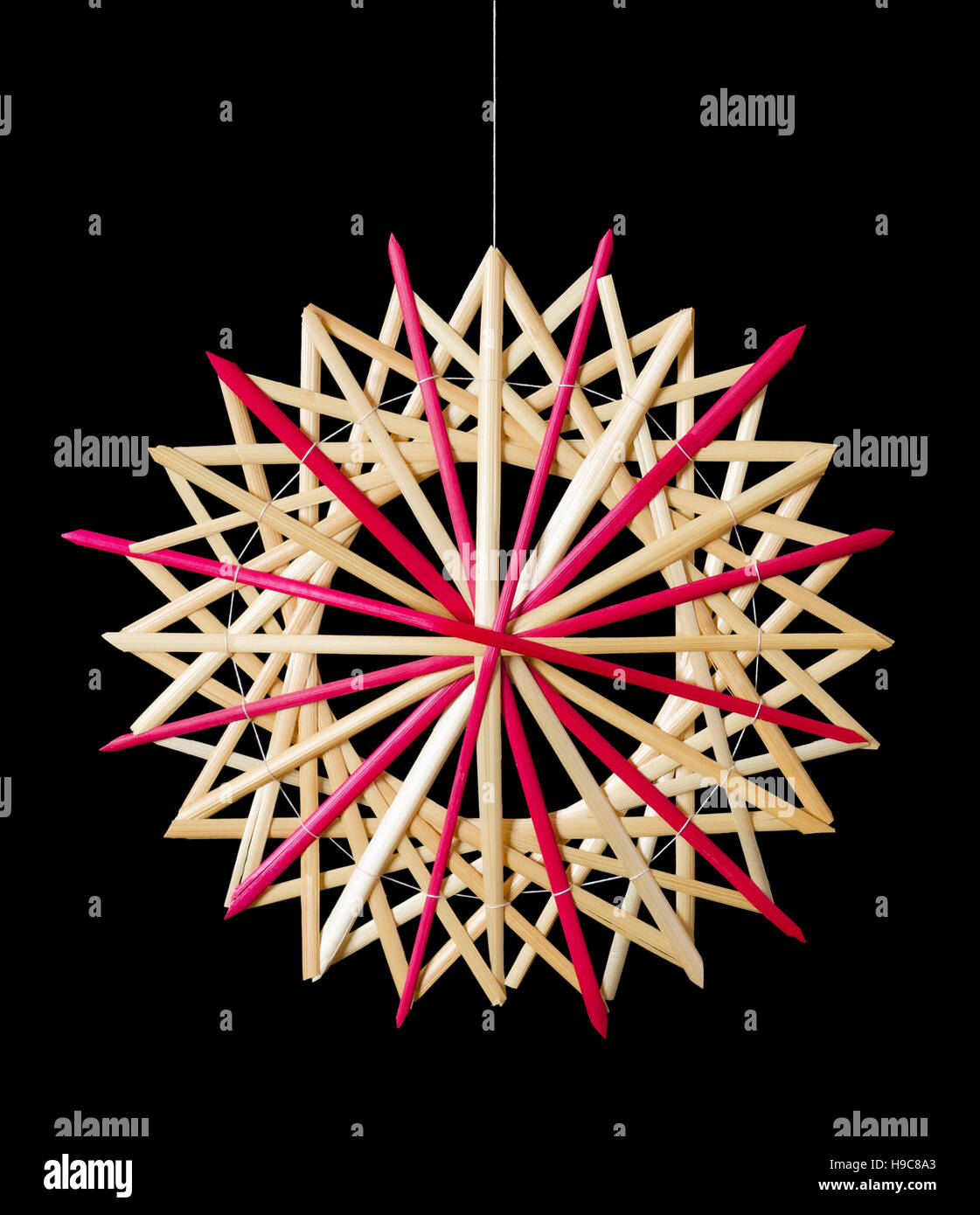 Stroh Weihnachtsdekoration Stern auf schwarzem Hintergrund. Handgefertigte farbenfrohe Dekor für Windows, als Geschenk oder an den Weihnachtsbaum hängen. Stockfoto