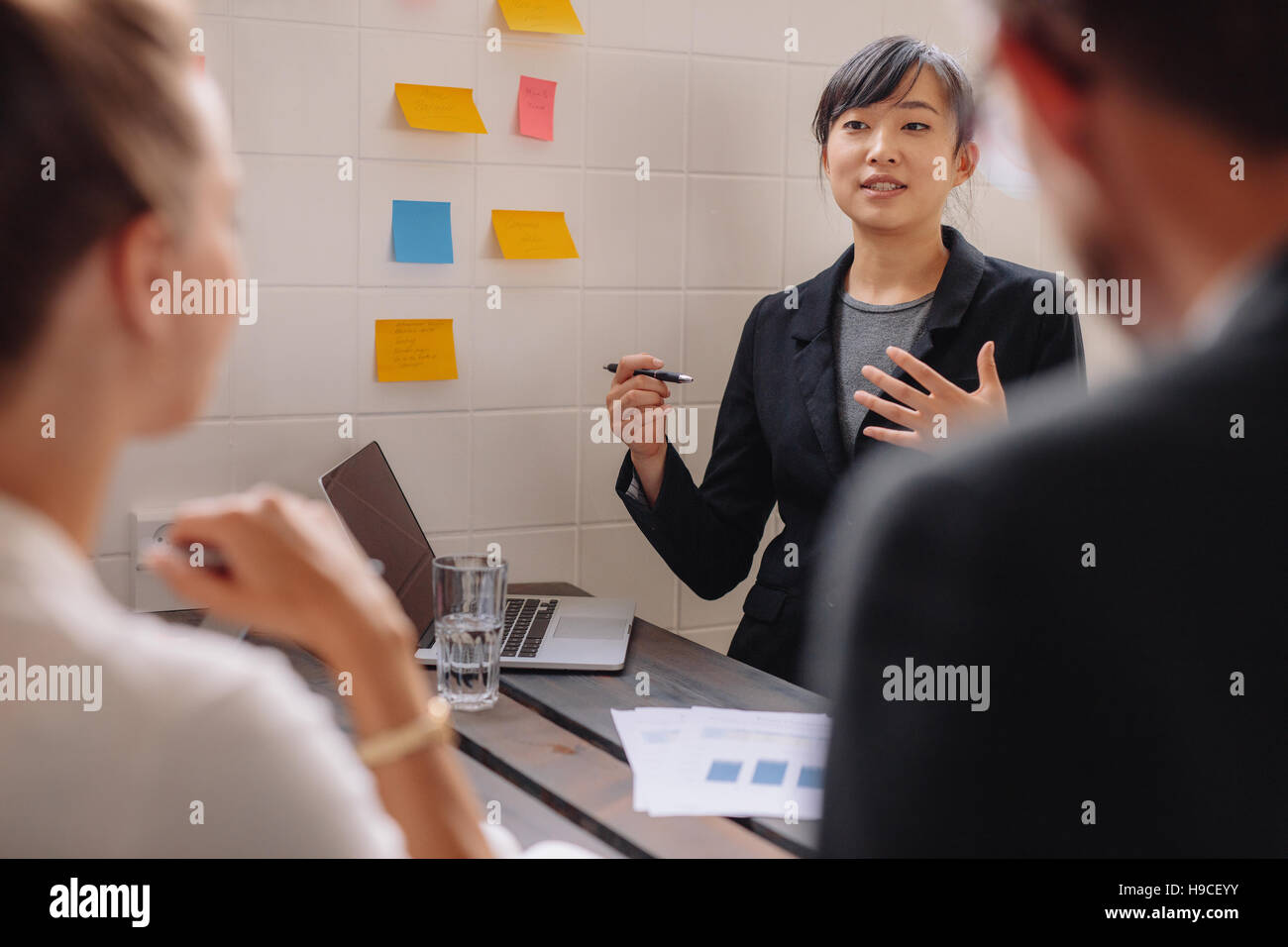 Asiatische Geschäftsfrau ihre neue Geschäftsideen, Kollegen zu erklären. Junge weibliche Führungskraft hält Vortrag mit Stick Notes an Wand. Stockfoto