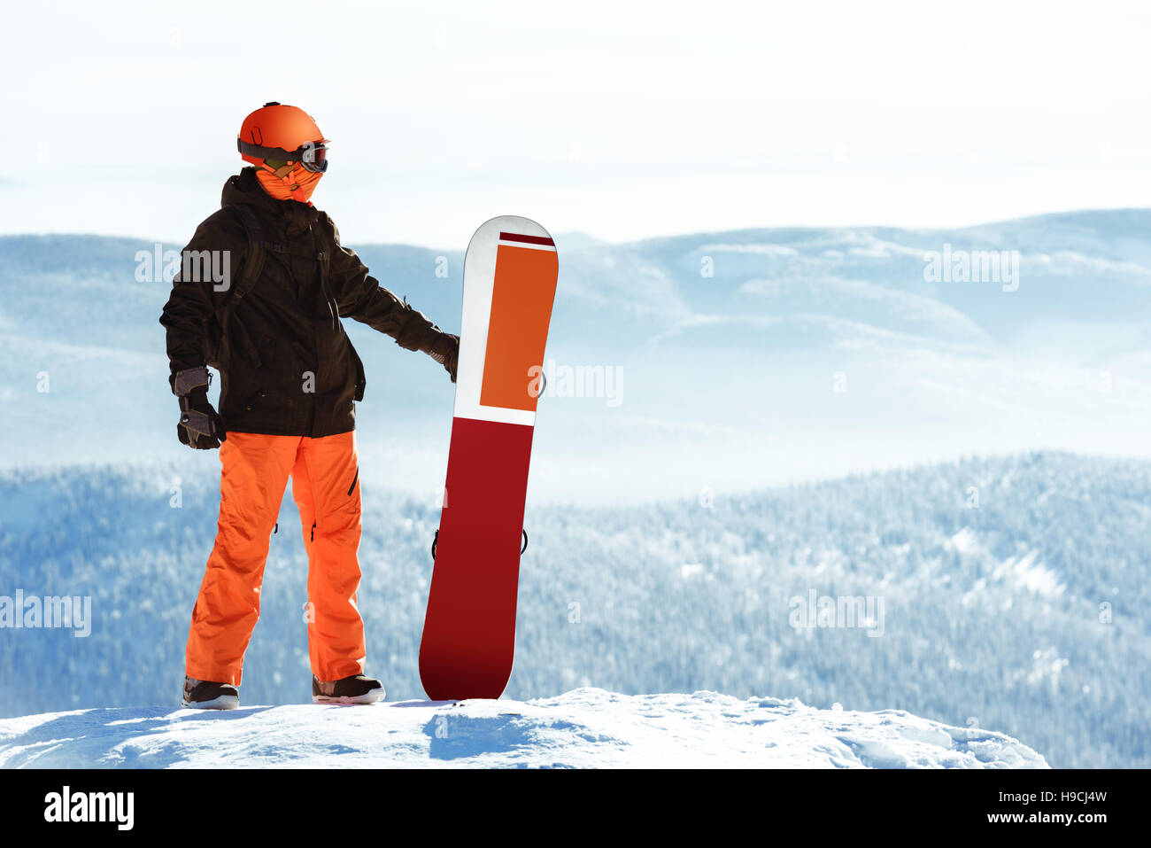 Snowboarder posiert mit Snowboard gegen Berge. Sheregesh Skigebiet Stockfoto