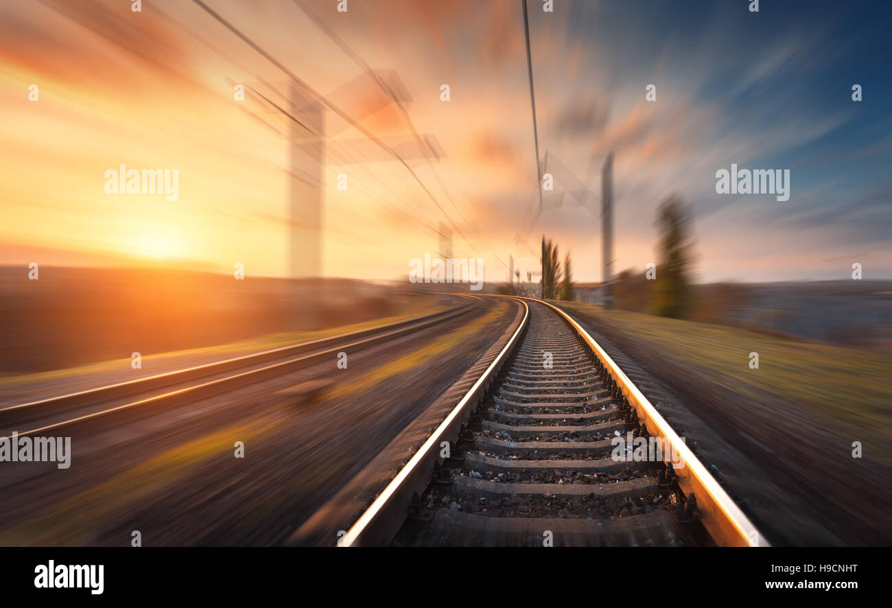 Eisenbahn in Bewegung bei Sonnenuntergang. Bahnhof mit Bewegung Unschärfe-Effekt gegen bunten blauen Himmel, industrielle Konzept Hintergrund Stockfoto