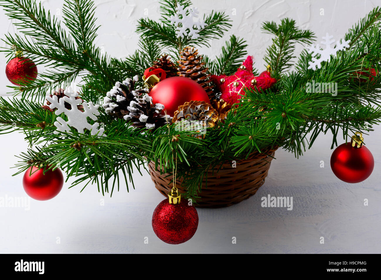 Rote Christbaumkugel dekoriert Herzstück in Weidenkorb. Weihnachten Gruß Hintergrund. Stockfoto