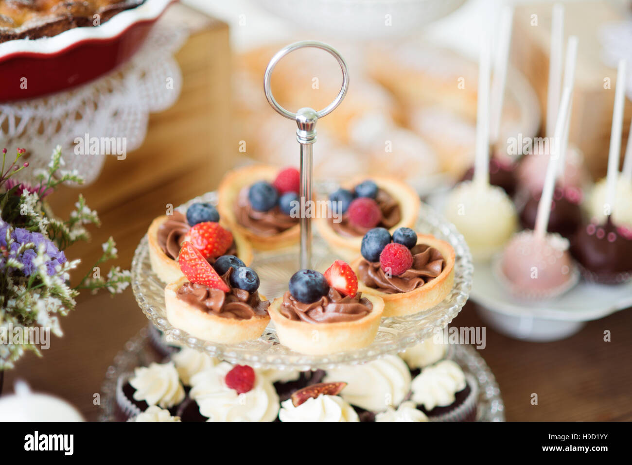 Tisch mit frischem Obsttorten, Cupcakes und bunten cakepops Stockfoto