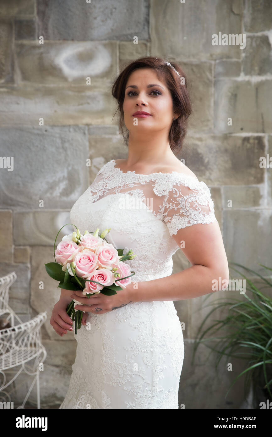 Schöne Braut mit rosa Blumen und Spitzenkleid Stockfoto