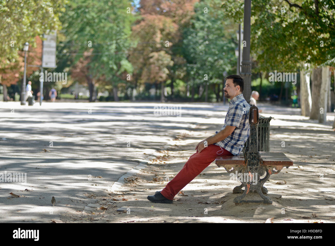 Mann mit Kopfhörer sitzen auf einer Bank in einem park Stockfoto