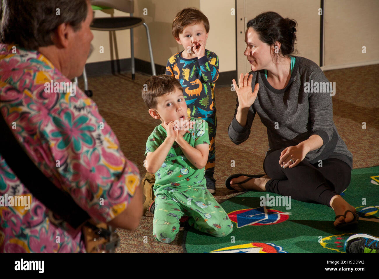 Zwei Pyjama gekleideten Jungen reagieren auf ein Konzert von einem Folk-Sängerin in einer öffentlichen Bücherei Mehrzweckraum in Laguna Niguel, CA. beachten Sie Mutter auf der rechten Seite. Stockfoto