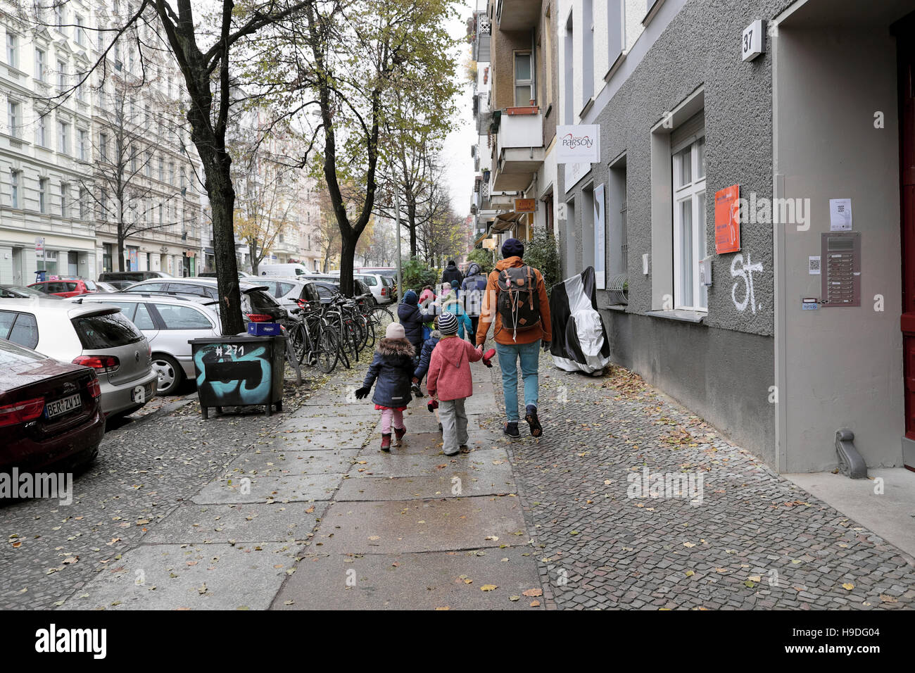 Rückansicht von Kindern, die an einem verregneten Herbstmorgen in einer Prenzlauer Berg Straße in eine Kindergärtnerei gehen Berlin, Deutschland Europa KATHY DEWITT Stockfoto