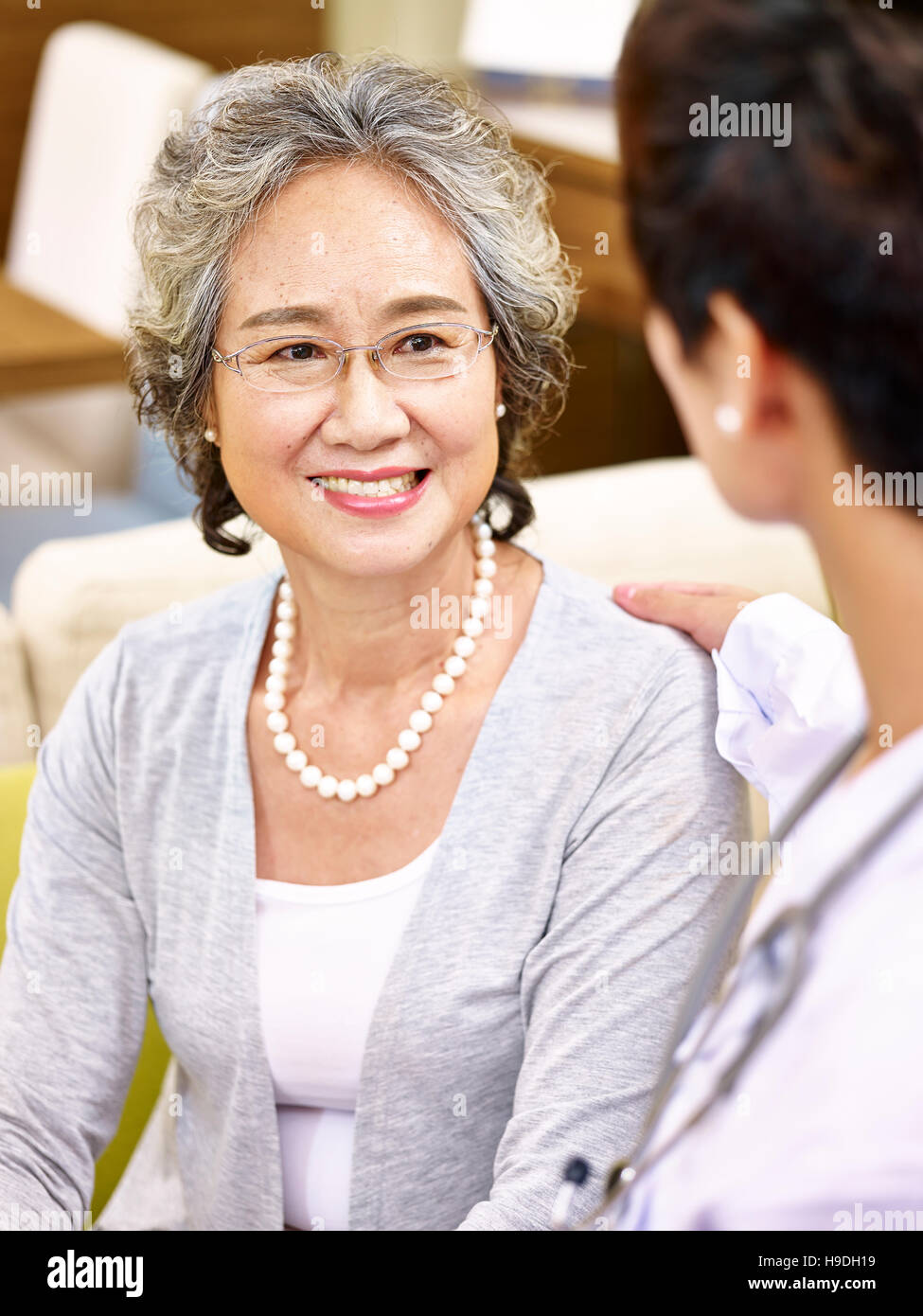 glücklich lächelnd senior asiatische Frau im Gespräch und wird von einer Ärztin getröstet. Stockfoto