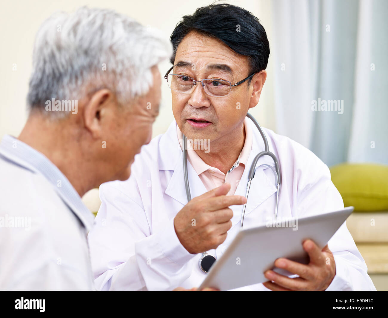 asiatischen Arzt gesundheitlichen Zustand, einen älteren Patienten zu erklären Stockfoto