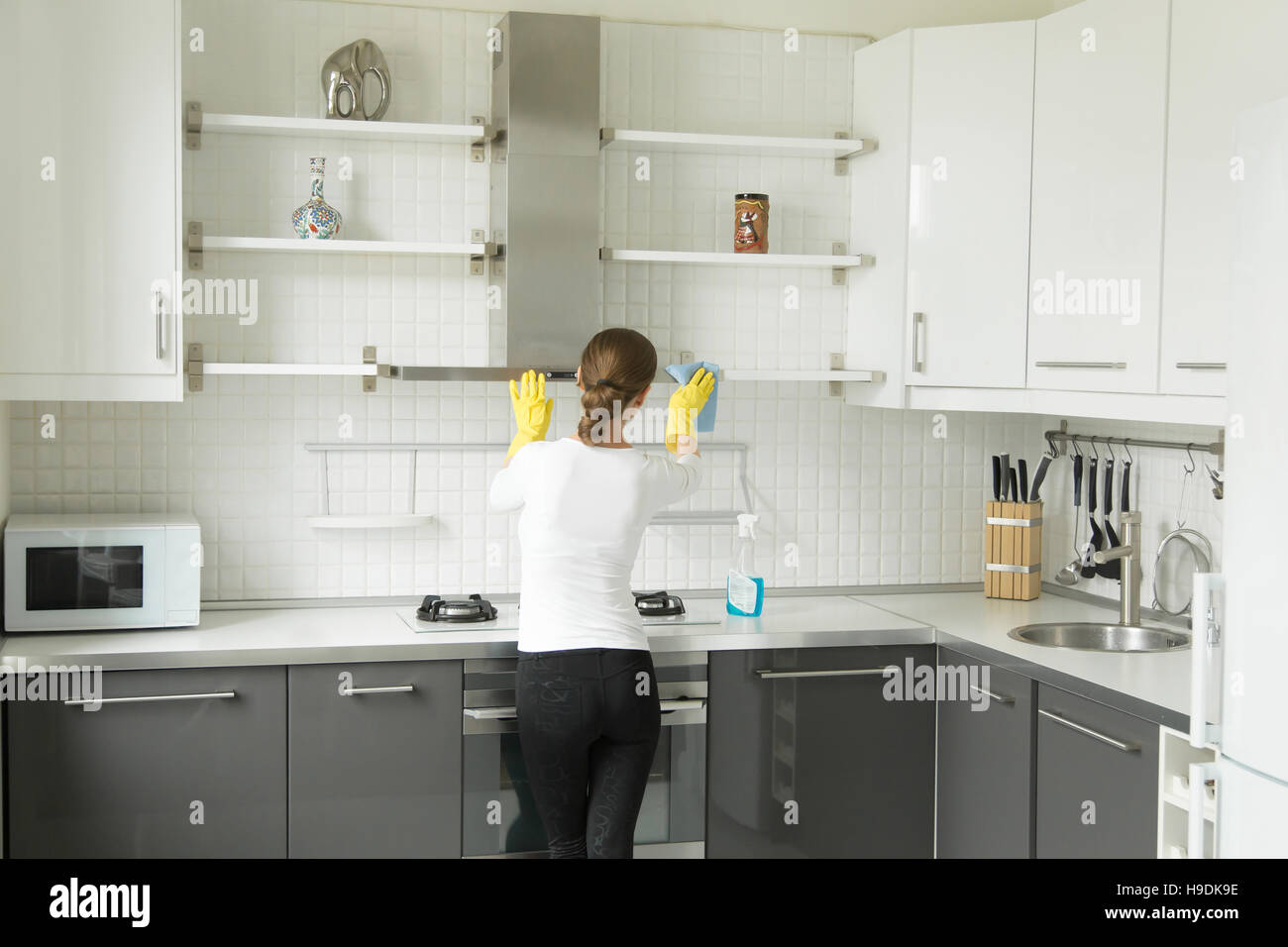 Ansicht von hinten auf eine junge Frau waschen Küche Schrank Stockfoto