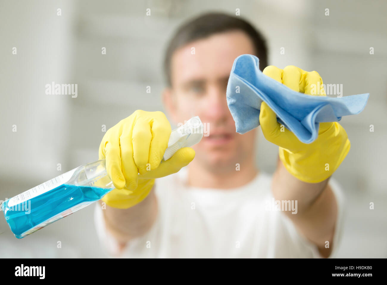 Nahaufnahme des männlichen Hände in Handschuhe halten Spray und Teppich Stockfoto