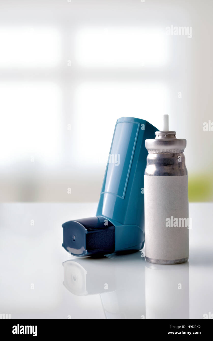 Patrone und blau Medizin Inhalator auf weißem Glastisch in einem Raum. Ansicht von vorne. Vertikale Zusammensetzung Stockfoto
