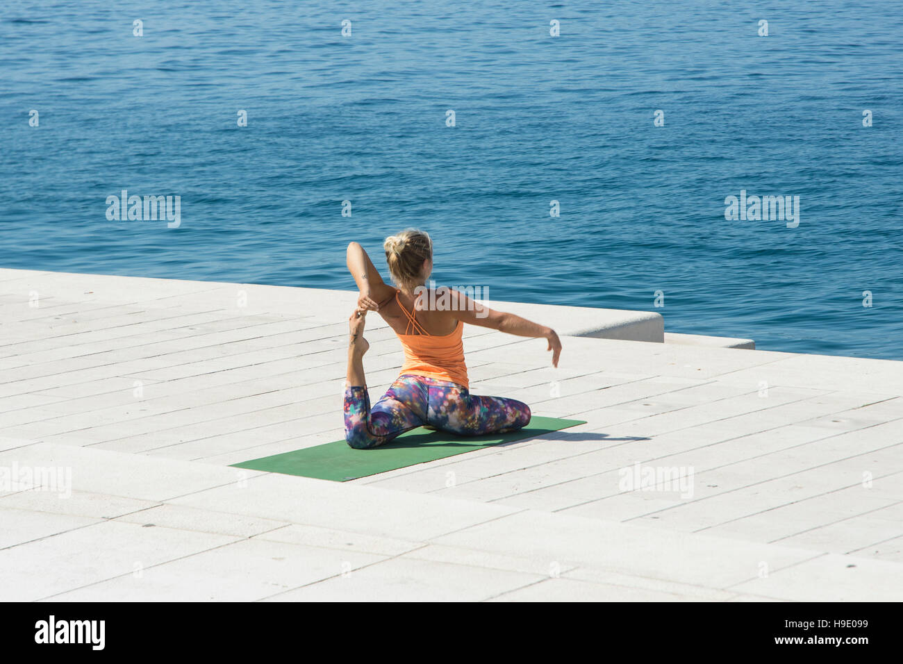 eine junge Frau dabei Yoga direkt am Meer Stockfoto