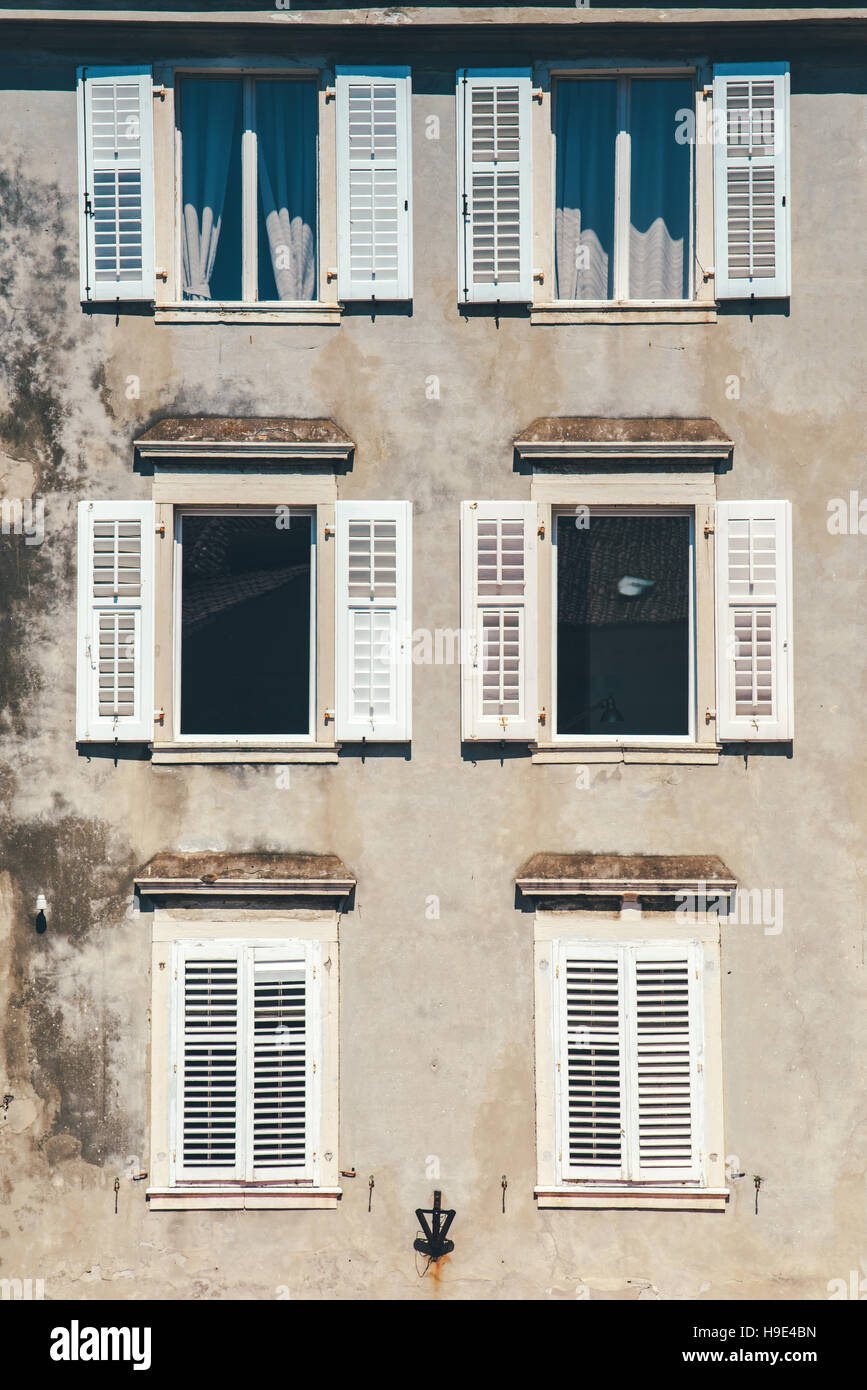Verwitterte Fassade und alte Fenster mit klassische venezianische Fensterläden aus Holz Jalousien, mediterranen Europa Architektur Vintage-Stil Stockfoto