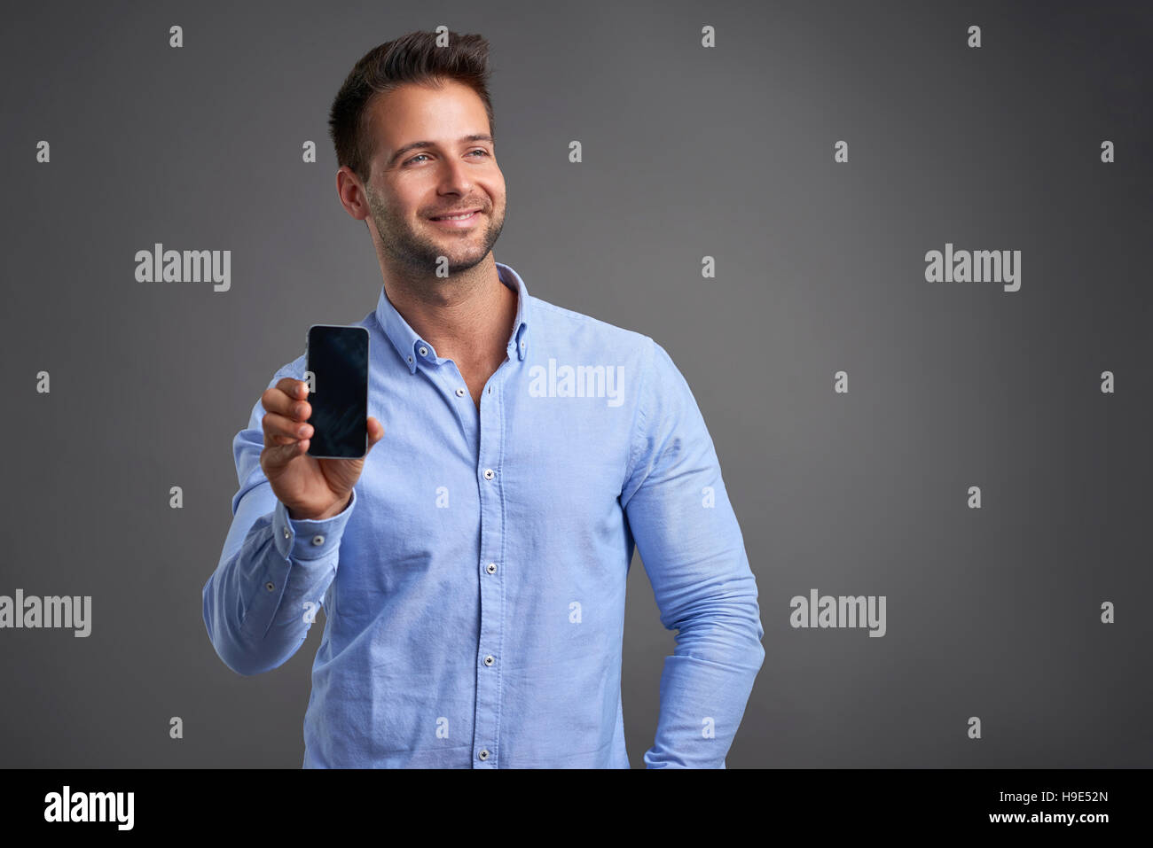 Ein zuversichtlich hübscher junger Mann mit seinem Handy auf die Kamera Stockfoto