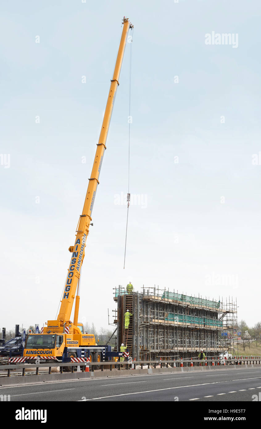 Ein mobiler Kran unterstützt den Bau eines neuen Brücke Piers in den Mittelstreifen der Autobahn M40, Oxfordshire, Vereinigtes Königreich Stockfoto