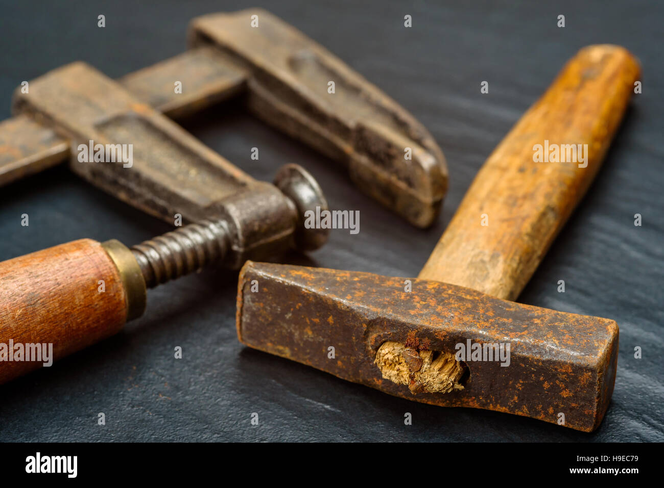 Alt und gut gebraucht handgemachte quadratische Hammer mit kurzer Holzgriff und Hand-Schraubzwinge auf dunklem Hintergrund. Stockfoto