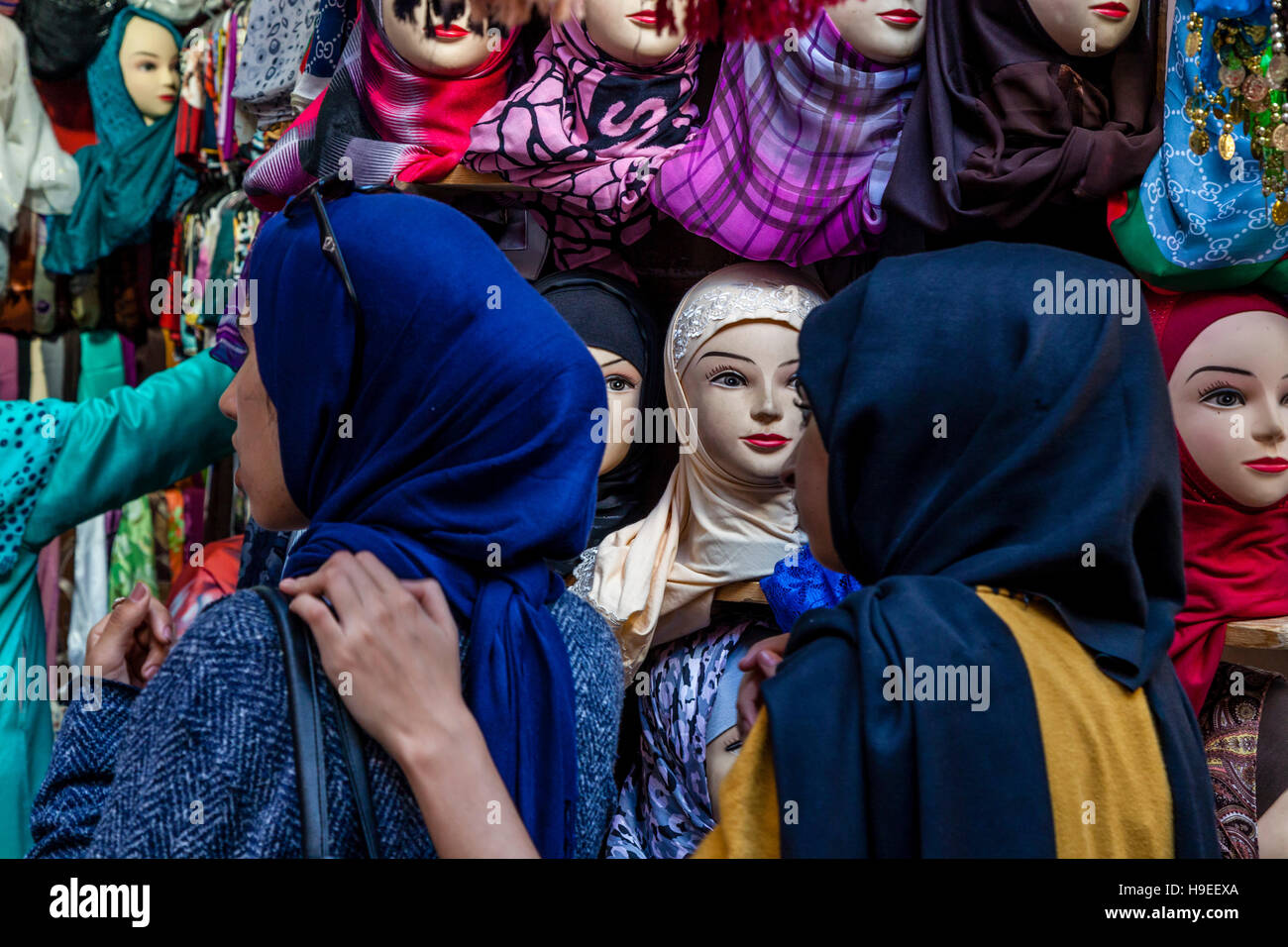 Zwei junge Frauen suchen bei Kopftücher für Verkauf an A Shop In The Medina, Fes el Bali, Fes, Marokko Stockfoto