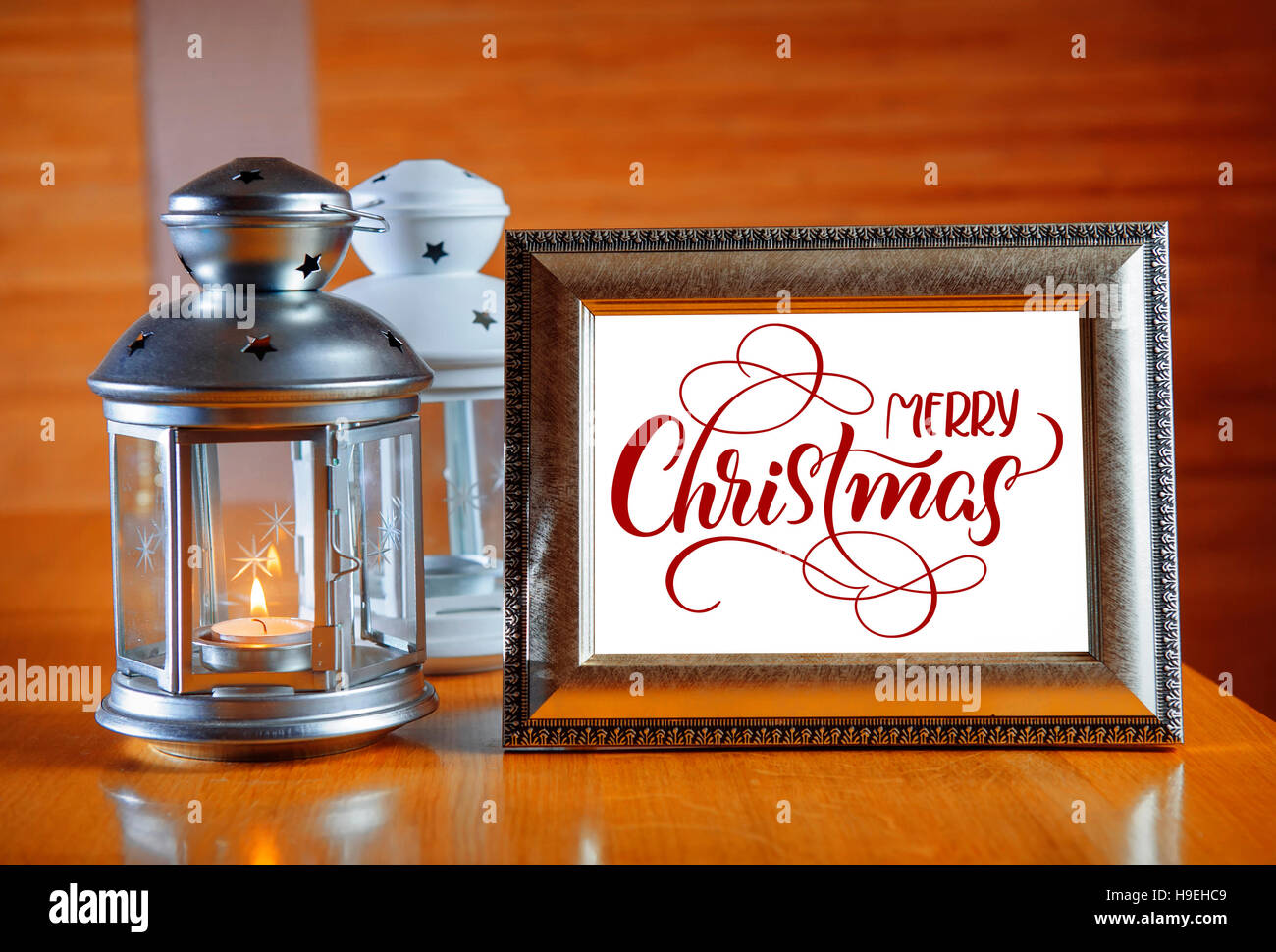 Rahmen auf dem Holztisch mit Text Frohe Weihnachten. Kalligraphie-Schriftzug Stockfoto