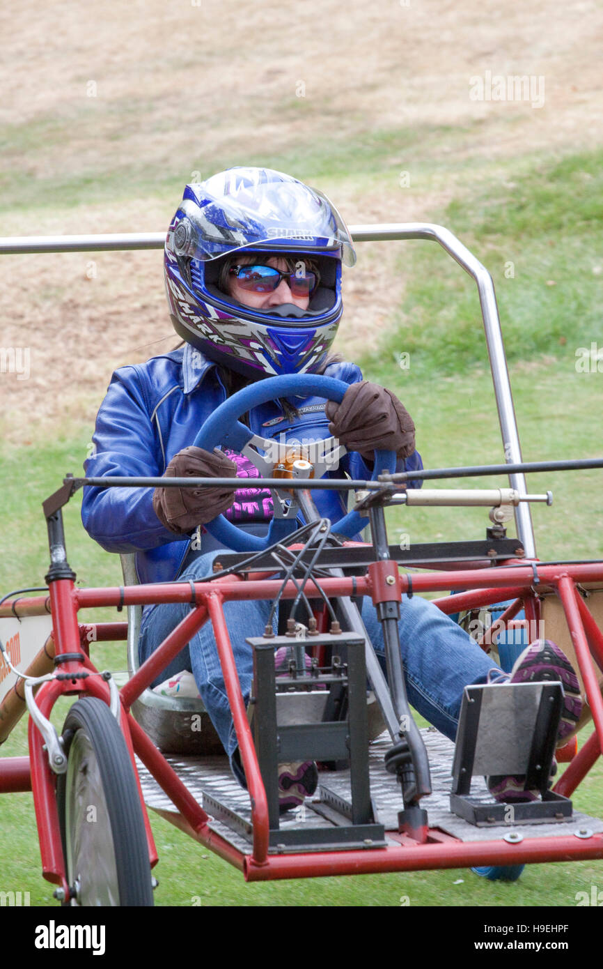 Mit Sonnenbrille und full-Face Helm ein Fahrer Rennen bergab eine Seifenkiste Stockfoto