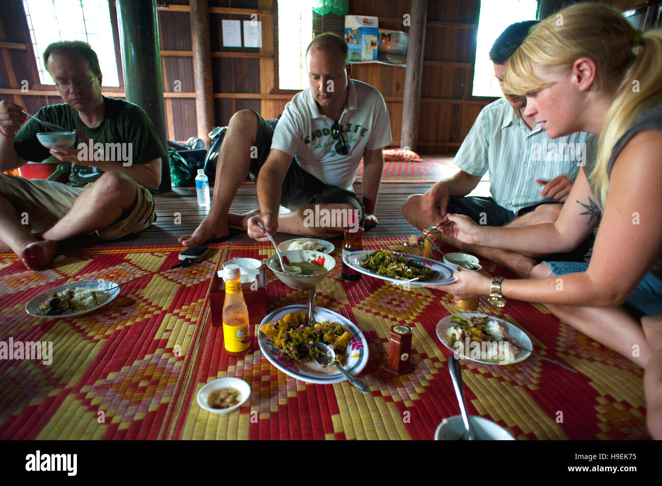 Ausländer essen Mittagessen in eine Community-basierte Home Aufenthalt auf Koh Trong, einem verarmten Insel im Mekong in Kambodscha. Stockfoto