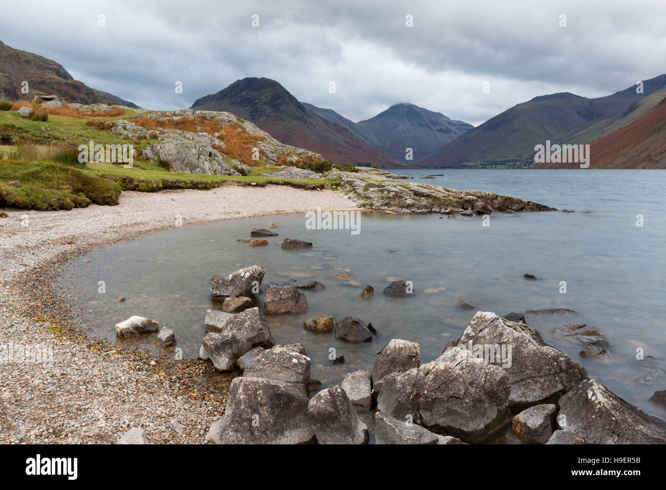 Felsiger Strand am Ufer des Wast Wasser in Cumbria, UK. Wasser durch lange Belichtungszeit unscharf. Stockfoto