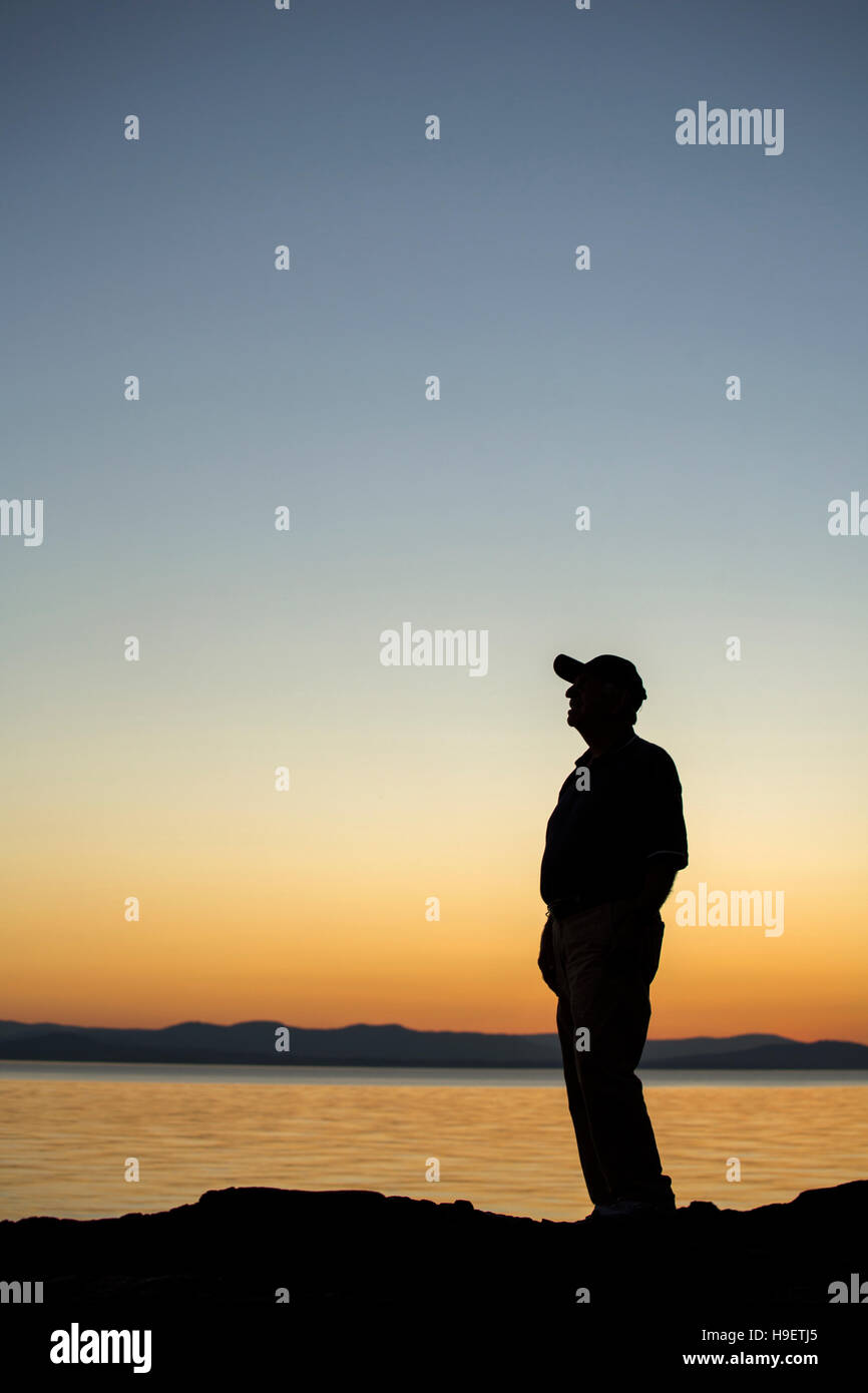 Silhouette des kaukasischen Mann in der Nähe von Wasser bei Sonnenuntergang Stockfoto