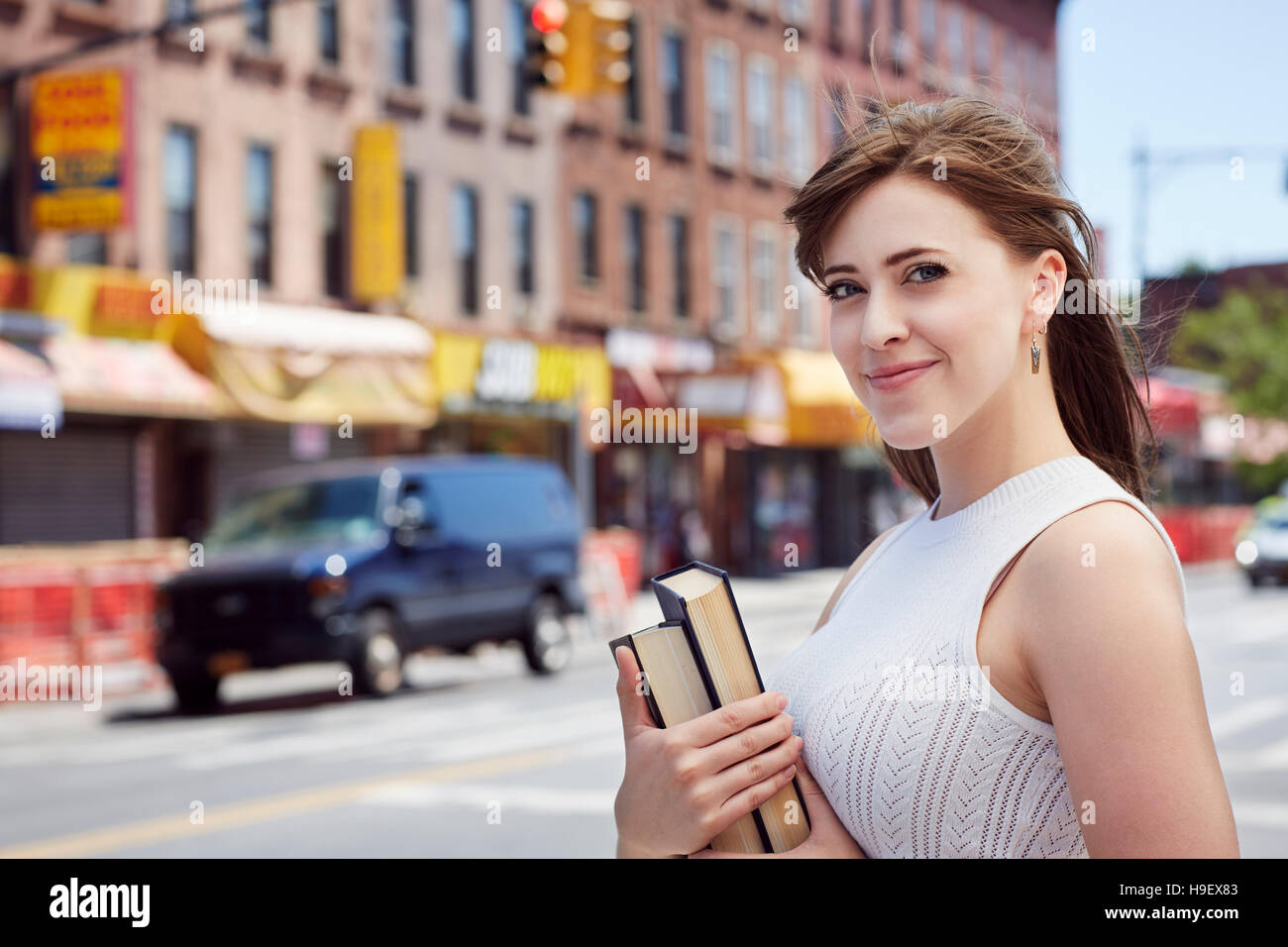 Kaukasische Frau, die Bücher über Stadt Bürgersteig Stockfoto