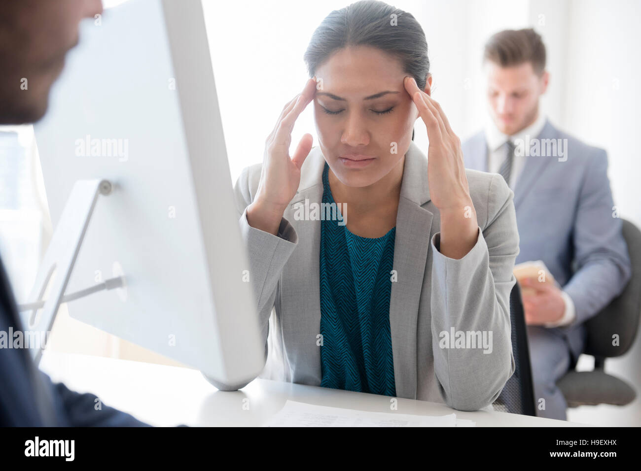 Geschäftsfrau mit Kopfschmerzen reiben Tempel im Büro Stockfoto