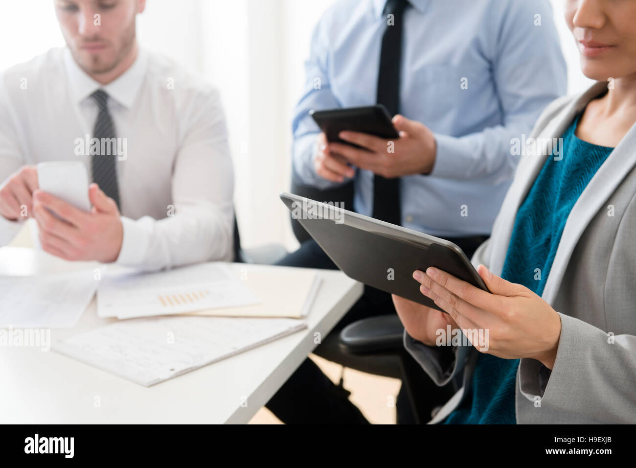 Geschäftsleute, die mit digitalen Brettchen und Handy im Büro Stockfoto