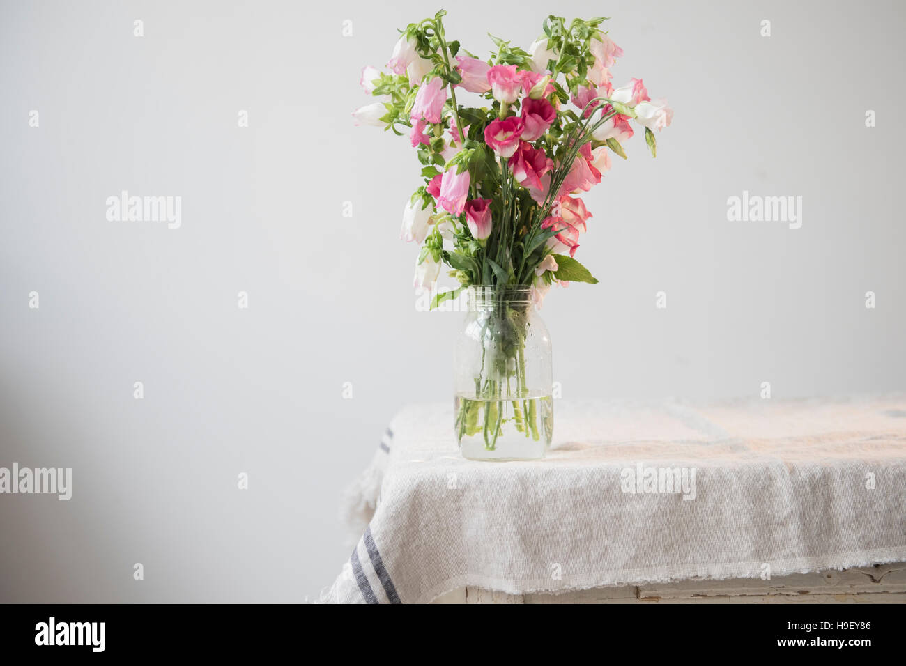Blumen in Glas Wasser am Rand der Tabelle Stockfoto